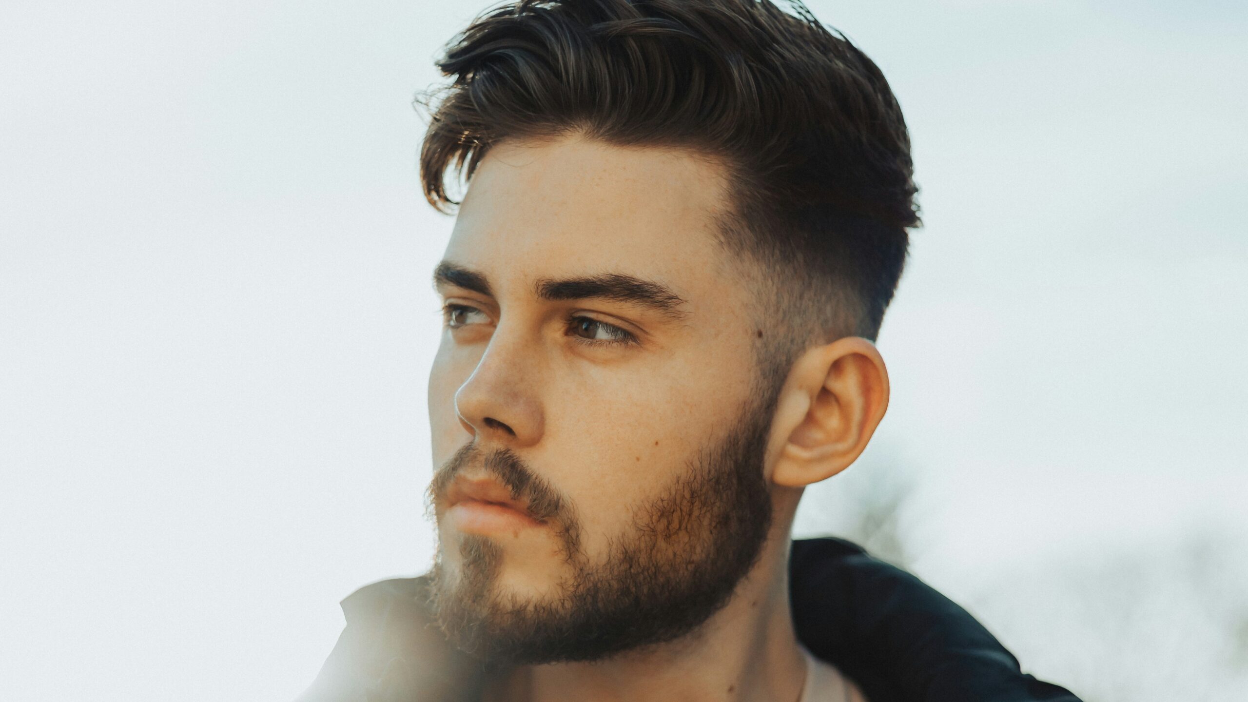 Man standing outside with dark hair featuring a taper fade haircut with a textured top