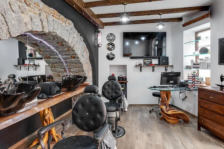 Rustic barber chair set against a stone arch feature wall at La Bottega di Pablo in the mountain town of Lanusei.