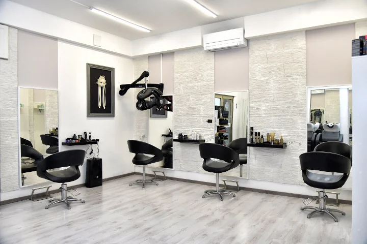Modern styling stations at Sp Beauty di Serena Pinna near the Pittulongu beaches in Olbia with black chairs and large mirrors.