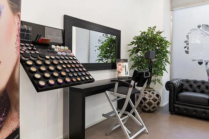 Bright manicure salon at Top Estetica in Villanova, Cagliari, with teal walls, floral desks and marble floors.
