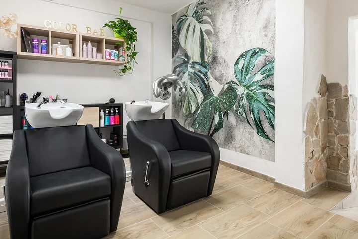 Hair-wash chairs and colour bar at Yourself salon in Tortolì with a tropical monstera wall mural.