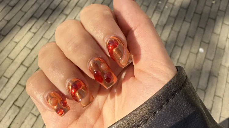 Lava nail art with amber and red swirls on a sheer base