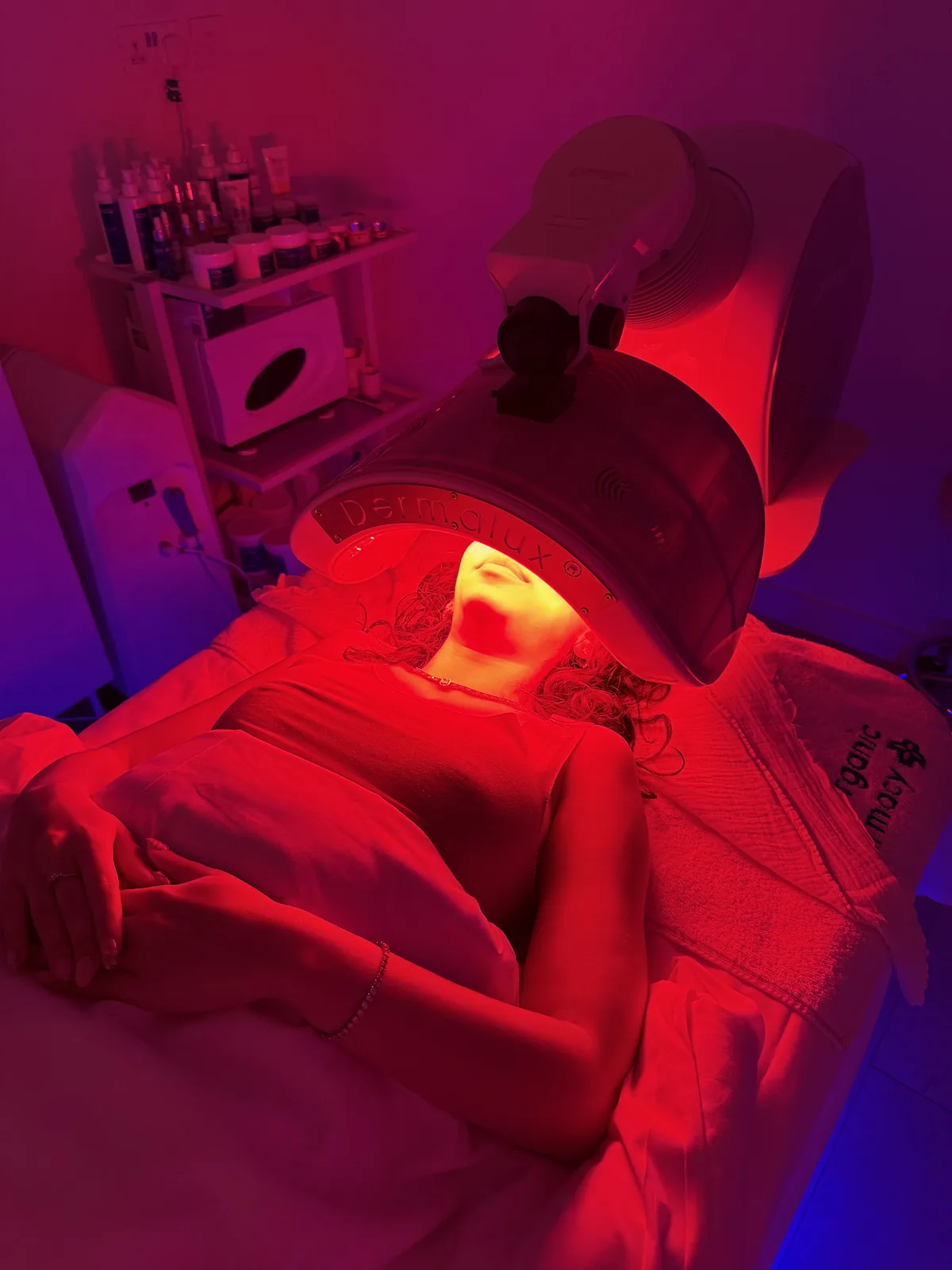 Woman relaxing under a red light LED panel during a spa treatment
